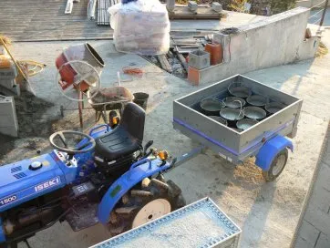 Le béton frais est chargé dans la remorque dans des seaux